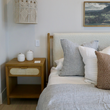 Bedroom with wooden nightstand, upholstered headboard, and decorative pillows.